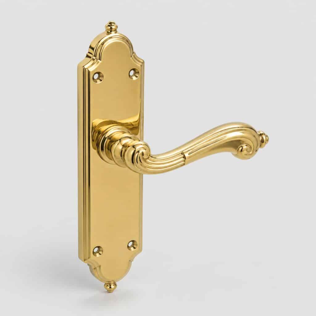 Poignee de porte ancienne en laiton poli dore de forme travaillee